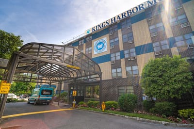 Front view of Kings Harbor Multicare Center with van and entrance