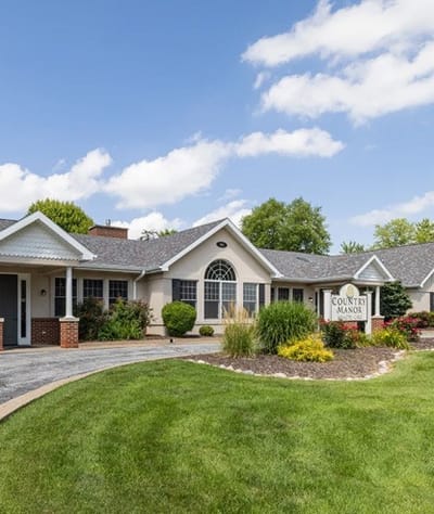Exterior view of Country Manor with landscaping and sign.