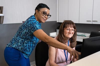 Staff assisting residents at a computer workstation