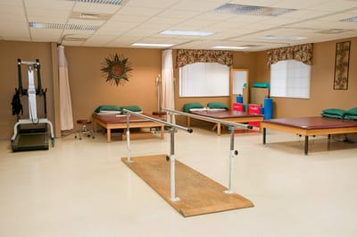 Physical therapy room with exercise equipment and parallel bars