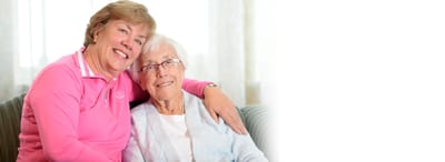 A caregiver and a resident smiling together on a couch