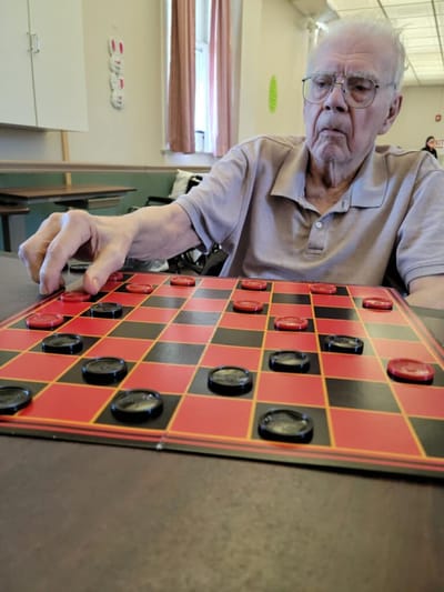 Senior man playing checkers in an activity room