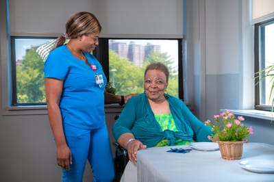 Staff member assisting a resident in a bright room
