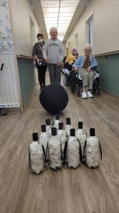 Residents participating in a bowling activity in the hallway