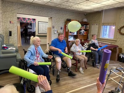 Residents engaging in a group activity with pool noodles