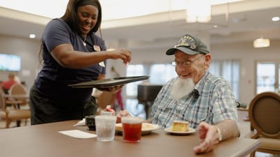 Staff serving food to a resident in the dining room