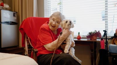 Resident smiling while holding a small dog