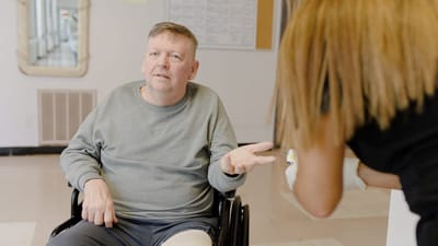 A resident in a wheelchair interacting with a staff member