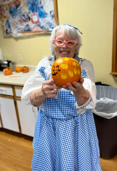 Resident showing off a decorated pumpkin in an activity room
