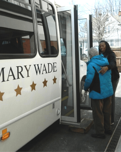 Staff assisting a resident boarding a facility transport vehicle