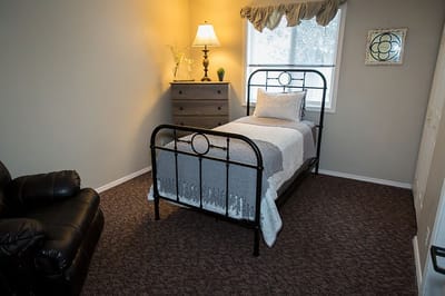 A private resident room with a bed and dresser