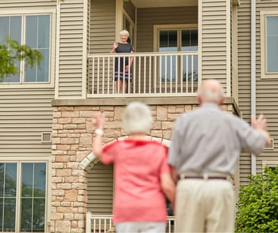 Residents waving from a balcony to another resident