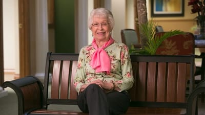 Resident smiling on a bench in a common area
