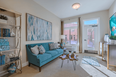 Bright and cozy common area with a teal couch