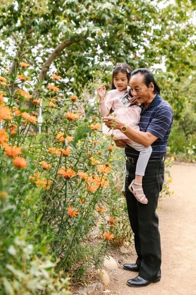An elderly man and a girl interacting in a garden