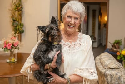 An elderly woman holding a small dog in a cozy living space