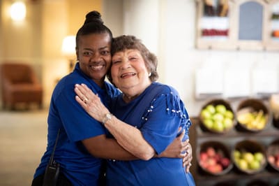 Staff member hugging a resident in a cheerful setting