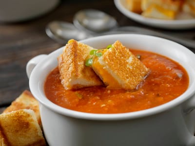 A bowl of tomato soup with grilled cheese croutons