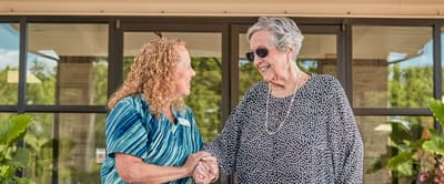 Staff member greeting a resident outside the facility