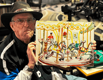 An elderly man holding a colorful painting of a carousel