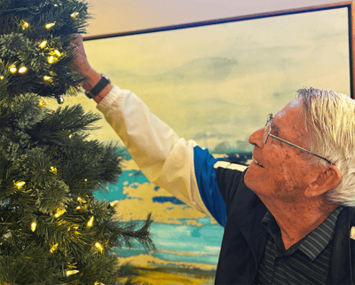 Resident decorating a Christmas tree with lights