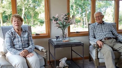 Two residents relaxing in a common area with large windows