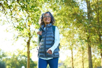 A woman walking in a park surrounded by trees