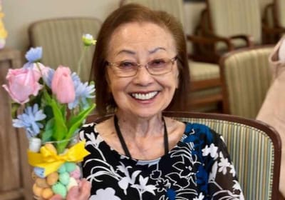 A smiling resident holding a bouquet of flowers in a common area