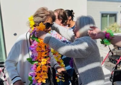 Residents celebrating with flower leis at a community event