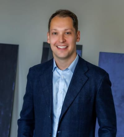 A young man in a blue blazer smiling