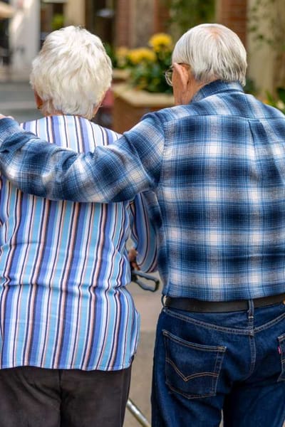 Two residents walking together in a sunny pathway