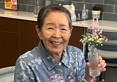Senior resident smiling with flowers in a common area