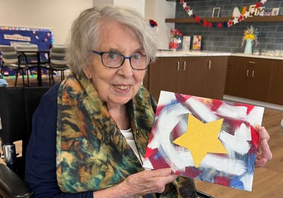 Resident showing artwork in an activity room