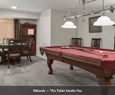 A billiards room with a pool table and chairs