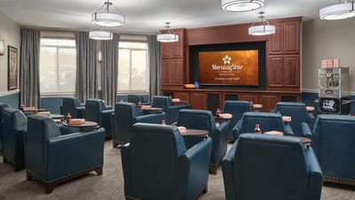 A common area with blue chairs and a presentation screen
