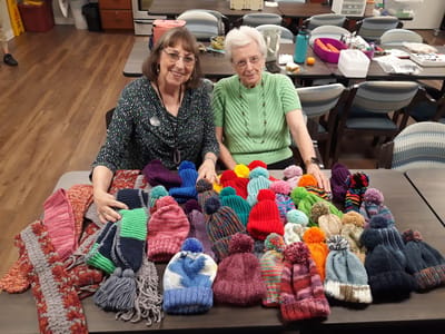 Residents showcasing handmade hats during a crafting activity