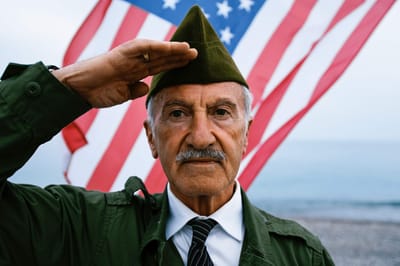 Elderly man saluting in front of an American flag