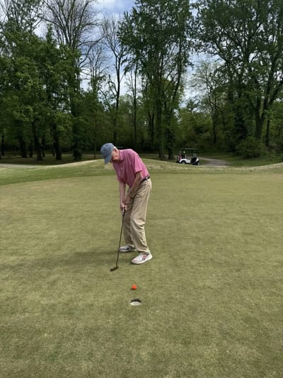 Resident playing golf on a green outdoor space