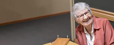 A smiling senior woman engaging in an activity.