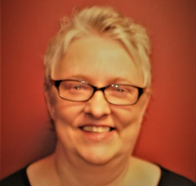Smiling resident with glasses against a red wall