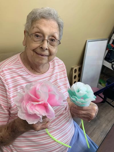 A resident holding handmade paper flowers