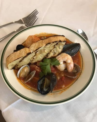 A bowl of seafood dish with bread on top