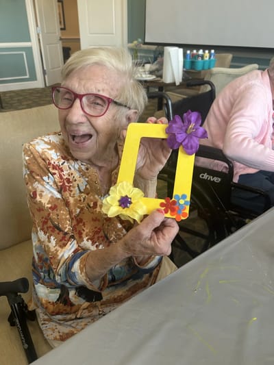 Resident participating in a craft activity with a frame.
