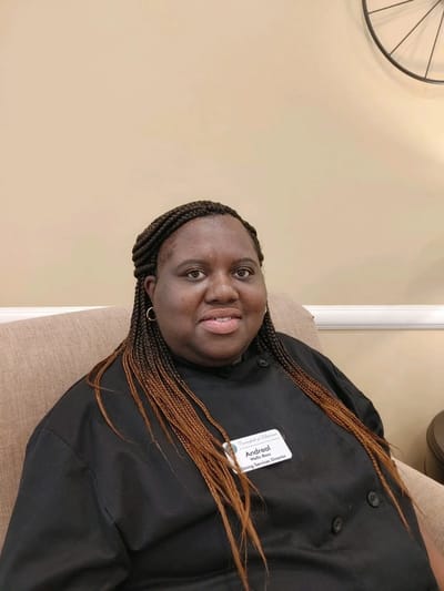 Staff member in a black chef uniform sitting in a lounge