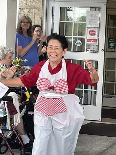 Resident celebrating in front of the facility with staff and others