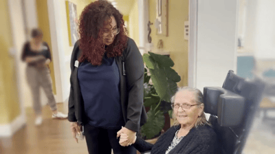 Staff member holding hands with a resident in a bright common area