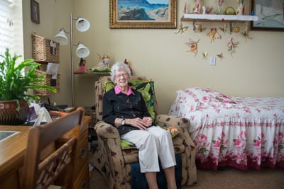 An elderly woman sitting in a comfortable chair in her room