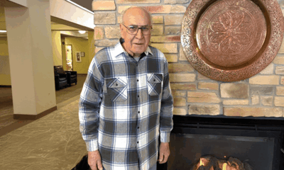 Senior resident standing in a common area by a fireplace