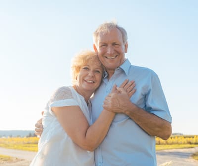 Senior couple embracing outdoors with backgrounds of fields