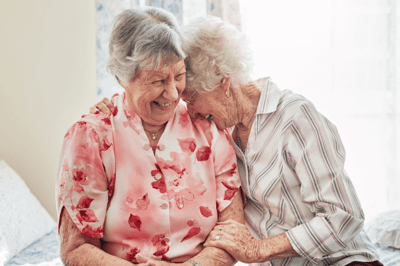 Two smiling elderly women enjoying a moment together